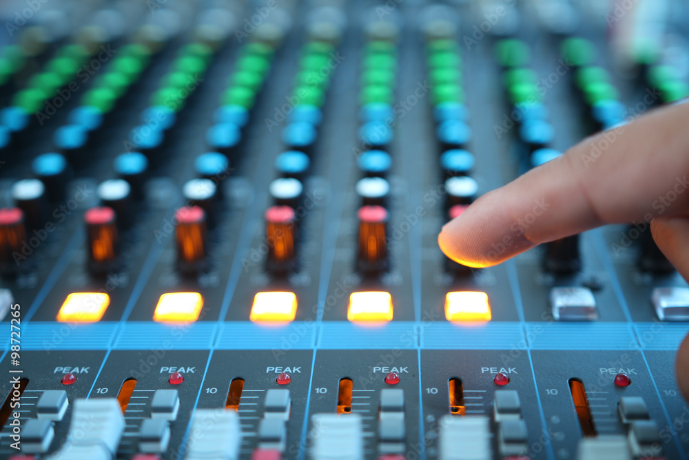 Close up of the rows of knobs and sliders on an analogue mixing