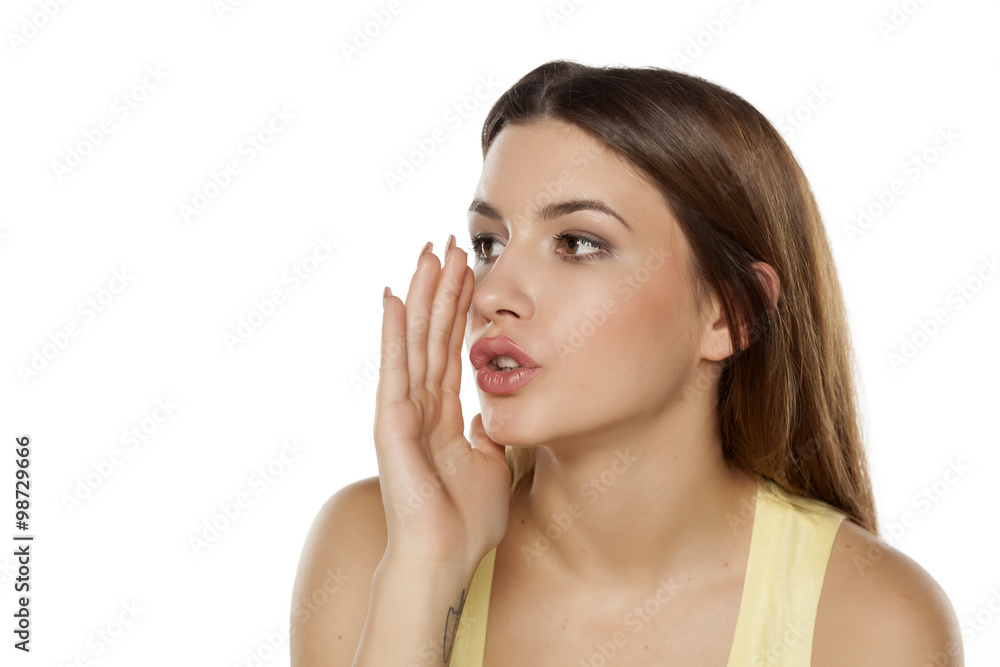 beautiful young woman whispers with a hand next to her mouth beautiful young woman whispers with a hand next to her mouth
