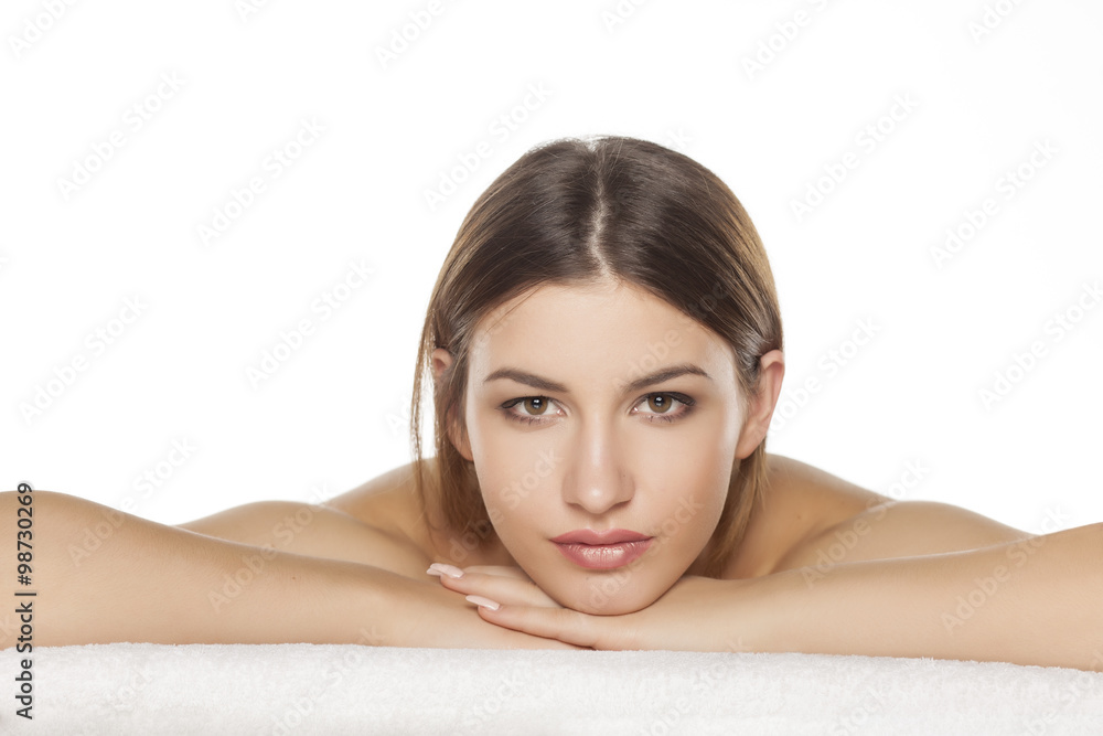 Portrait of a serious young woman is lying down on towel Portrait of a serious young woman is lying down on towel