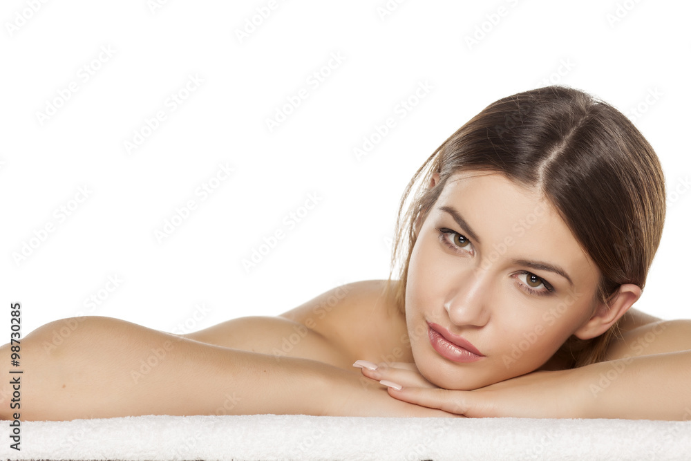 Portrait of a serious young woman is lying down on towel Portrait of a serious young woman is lying down on towel