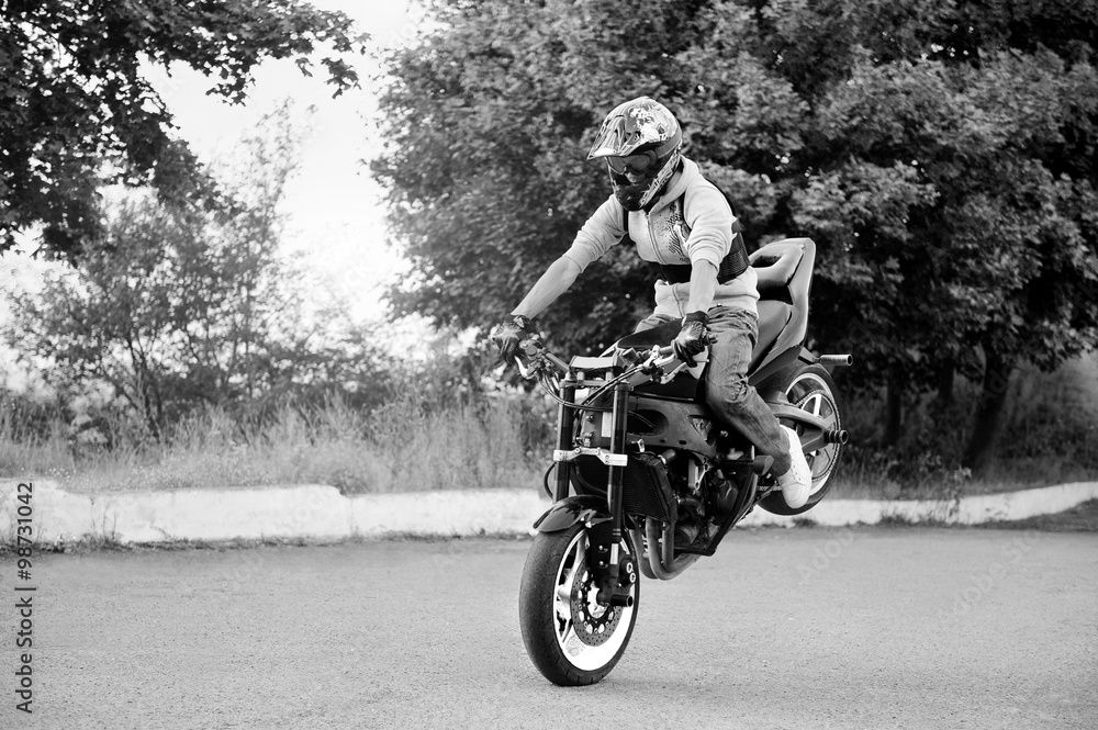Extreme hobby. Talented risky stuntmen riding his motorbike on the road black and white shot soft smudged focus