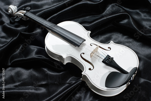 Closeup of a white violin on a background of  black satin