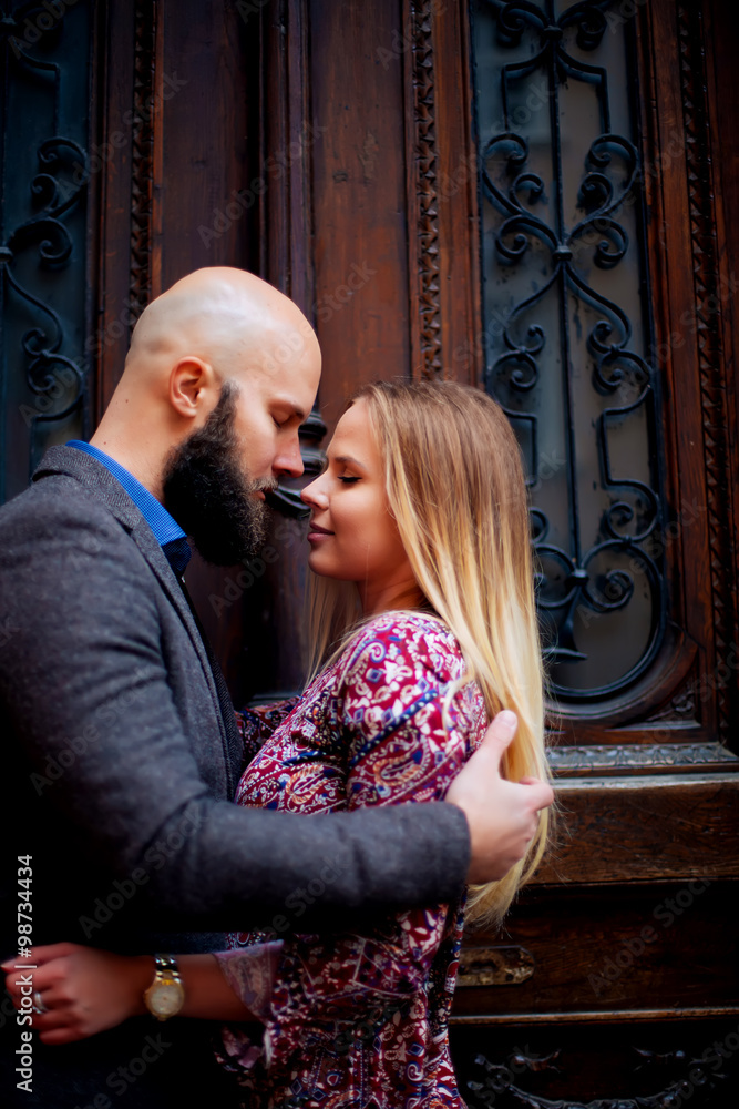 Happy couple low waist hugging and smiling, kissing on the background of old building Happy couple low waist hugging and smiling, kissing on the background of old building