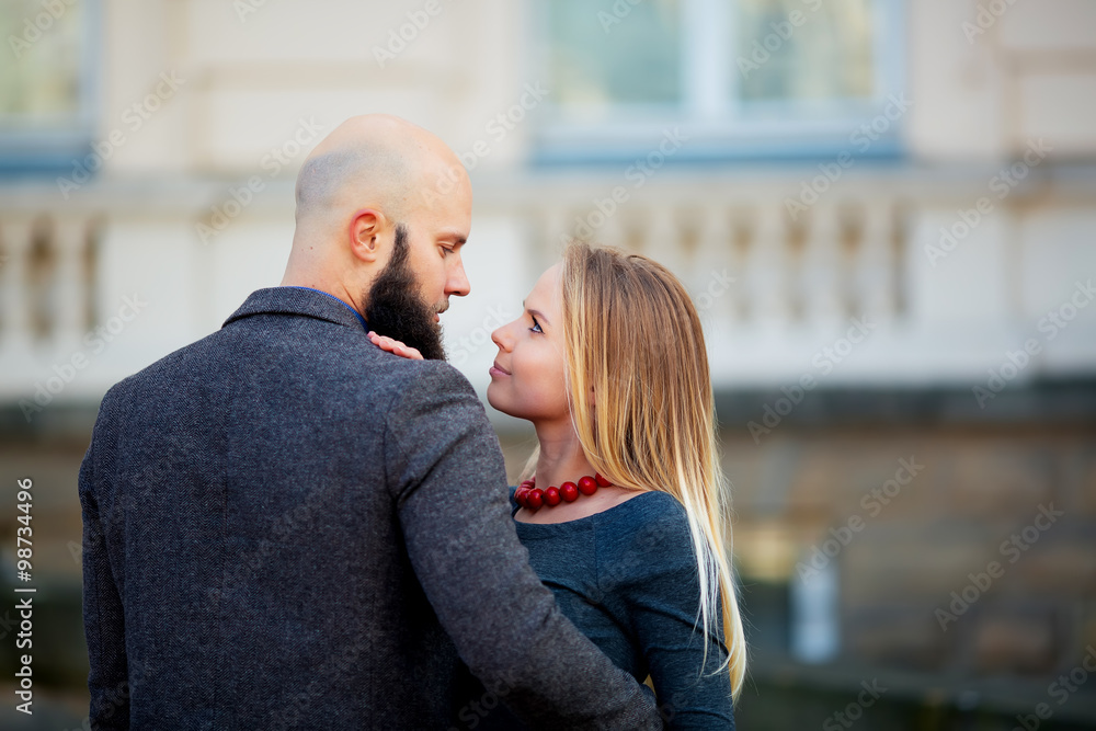 Fototapeta premium Portrait closeup couple of long-haired young sensual woman back arched touching beard of man with moustache bent over girl face holding hair grey background, vertical picture