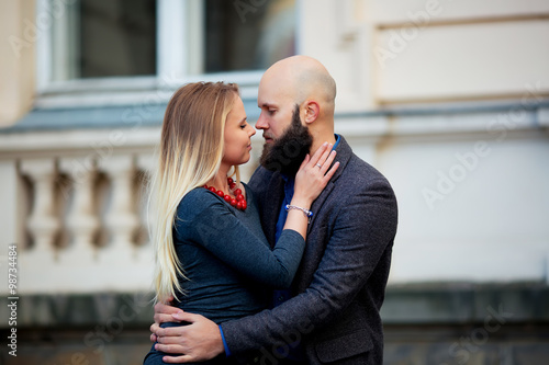 One beautiful stylish tender couple of young woman and senior man with long black beard embracing close to each other outdoor in spring sunny day