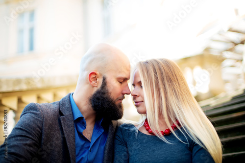One beautiful stylish couple of young woman and senior man with long black beard sitting embracing close to each other outdoor in autumn street on stairs sunny day, horizontal picture © ostap_davydiak