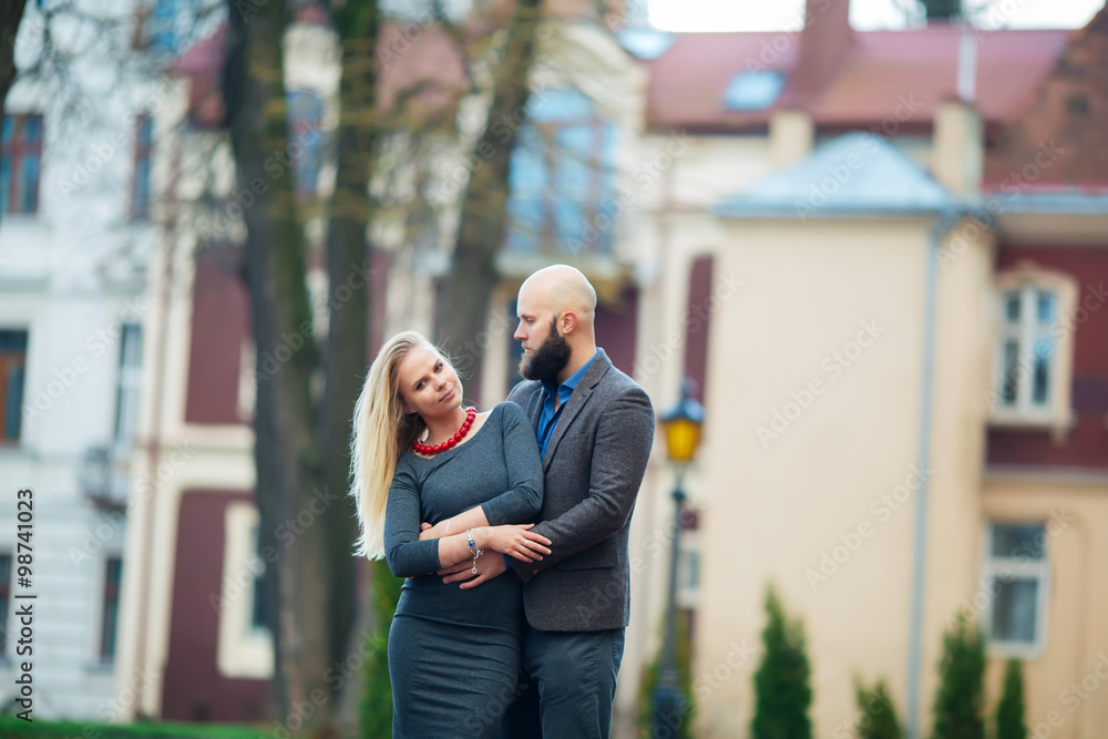 beautiful girl embraces the guy, stylishly dressed, bald man with a beard