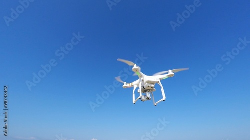 White remote controlled drone equipped with high resolution video camera hovering in mid air photo