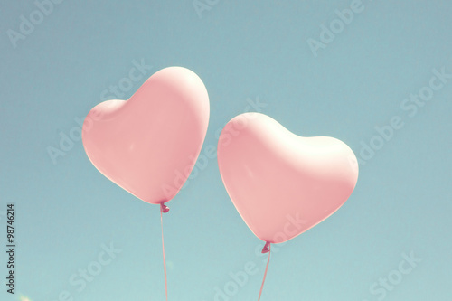 Two pink heart shaped balloons in turquoise sky