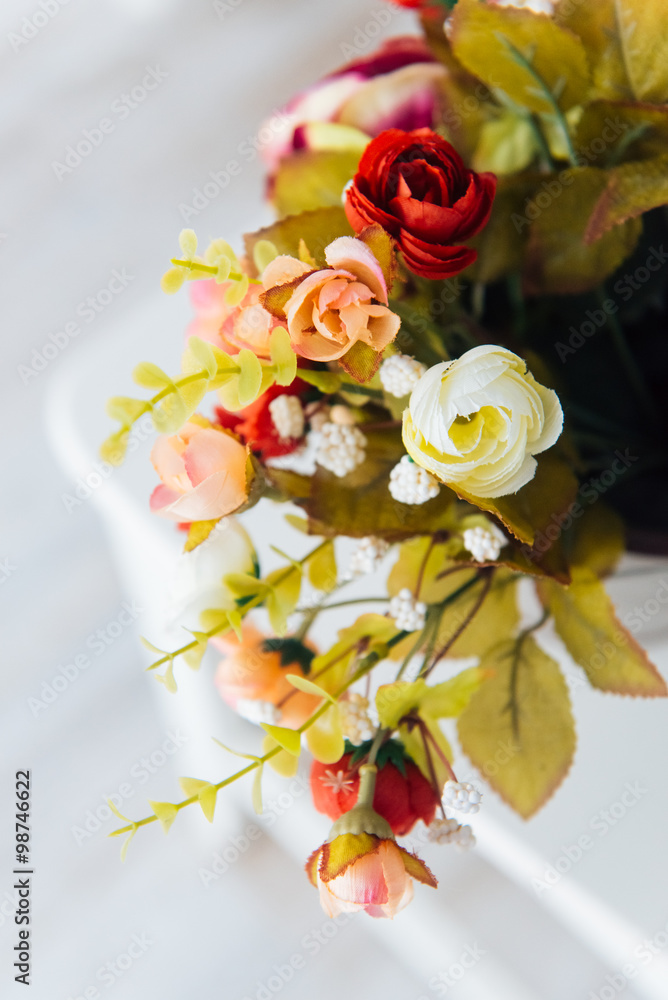 Pot with colorful  rose flowers standing on a white chair