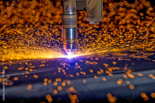CNC Plasma torch cutting steelplate with orange bokeh sparks