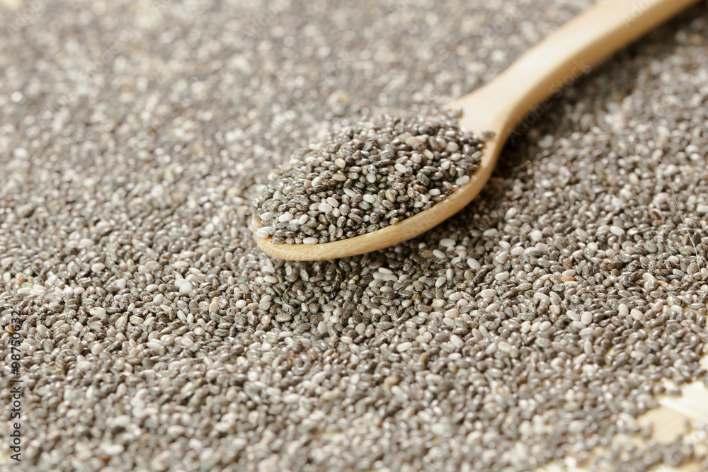 Handful of chia seeds on wood spoon and background Handful of chia seeds on wood spoon and background