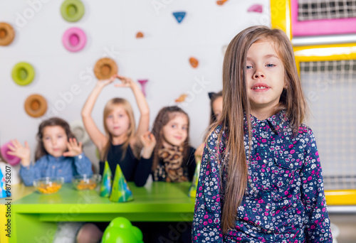 Smiling little girl with her friends at birthday party