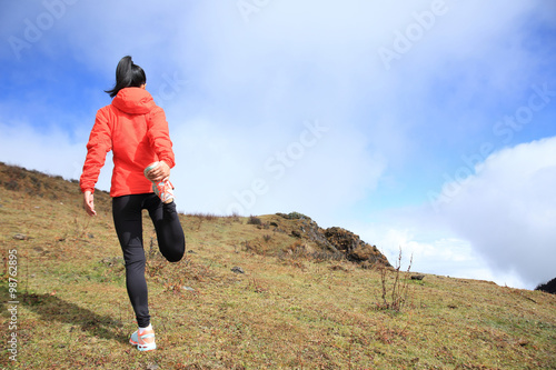 young woman trail runner warm up  on mountain peak