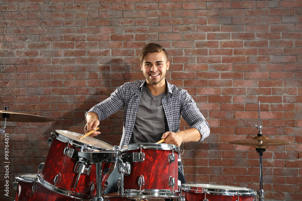 Musician playing the drums on brick wall background Musician playing the drums on brick wall background