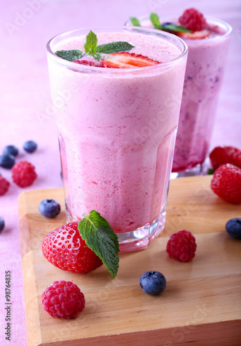 Milkshakes at cutting board with berries on light background, close-up