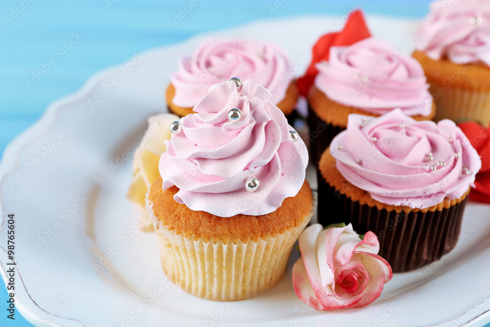 Tasty cupcakes on plate, on color wooden background