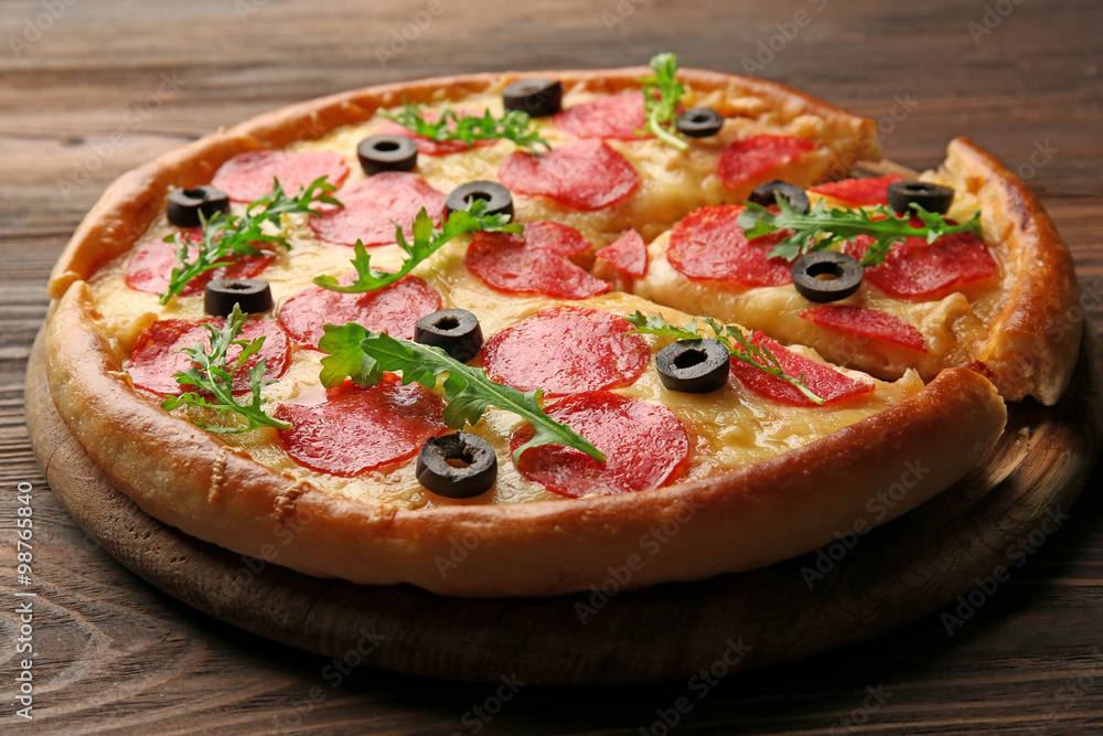 Hot tasty pizza with salami and olives on wooden background Hot tasty pizza with salami and olives on wooden background