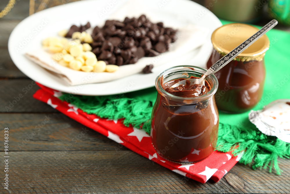 Chocolate dessert in small glass jars and morsels on plate, on wooden background Chocolate dessert in small glass jars and morsels on plate, on wooden background