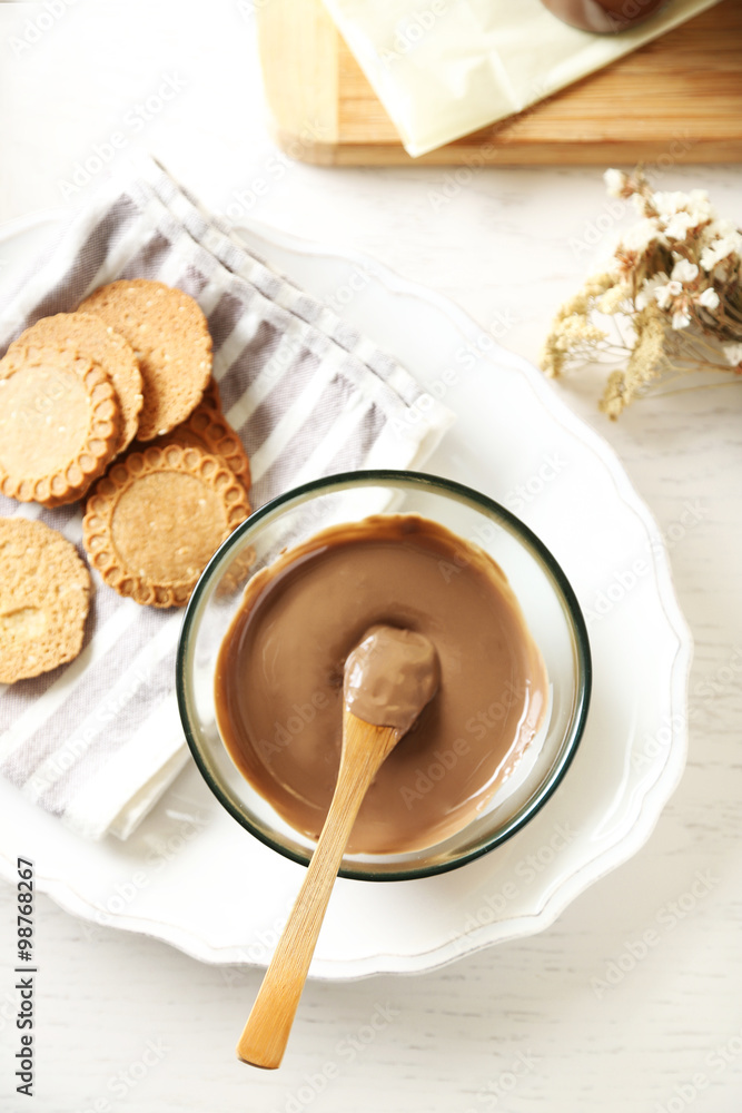 Melted chocolate on glass bowl, on wooden background Melted chocolate on glass bowl, on wooden background