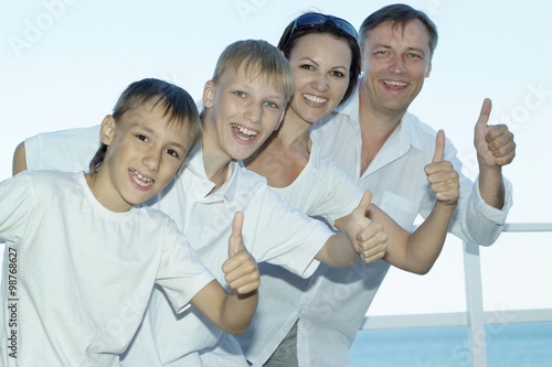 Happy family of four showing thumbs up