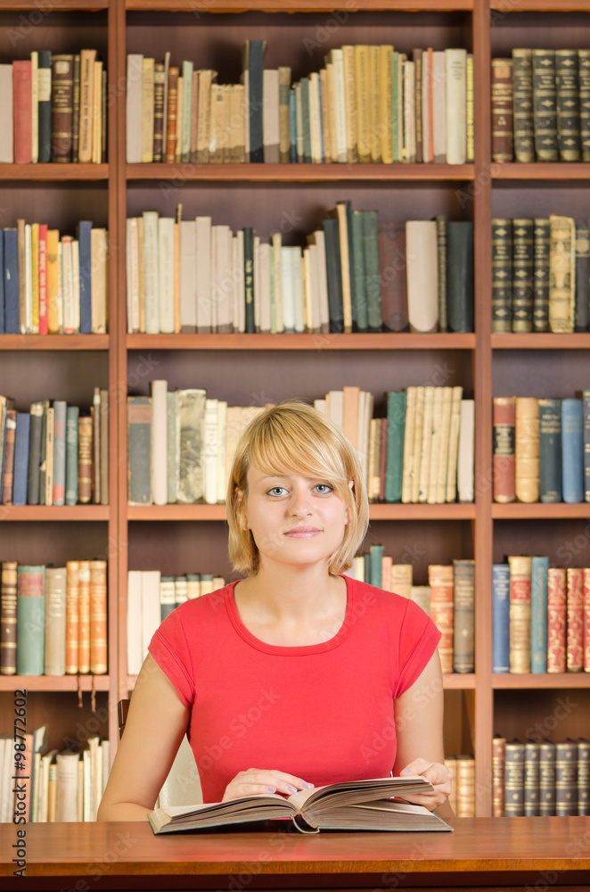 Girl with an open book at library table Girl with an open book at library table