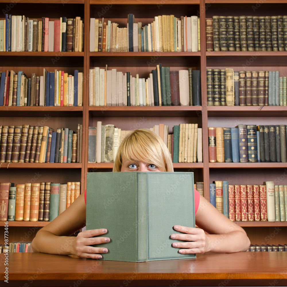 Girl with smiling eyes hiding behind a book (square composition) Girl with smiling eyes hiding behind a book (square composition)