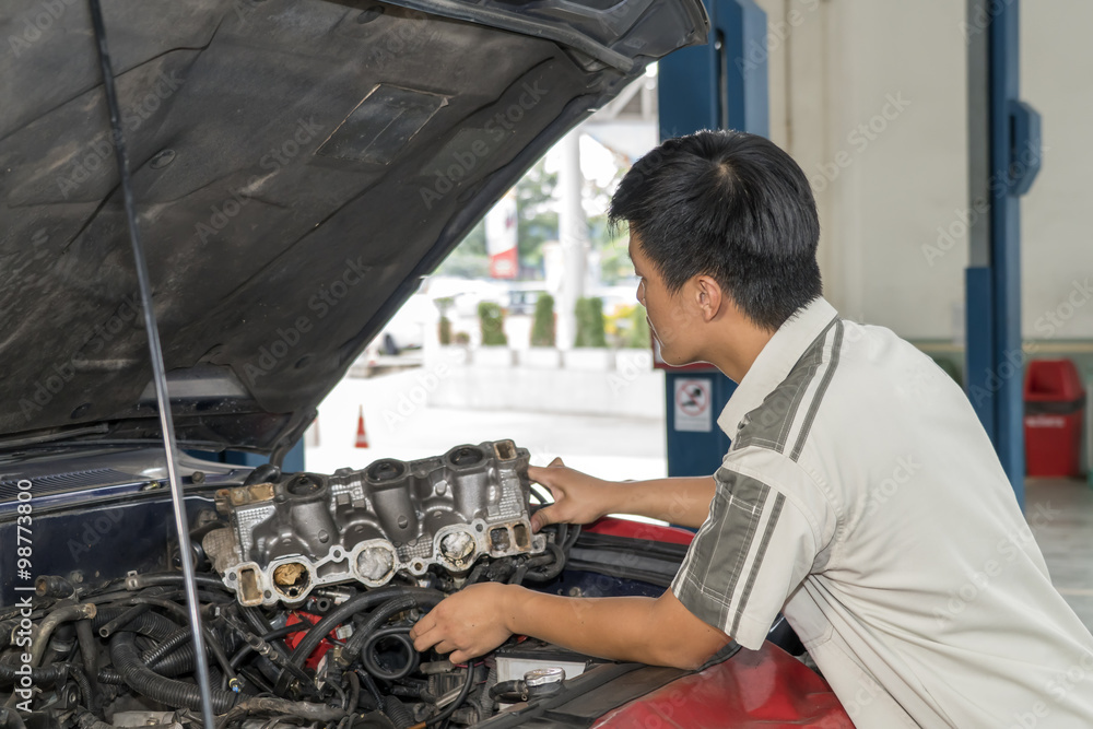 Obraz premium Young mechanic repairing car in service center