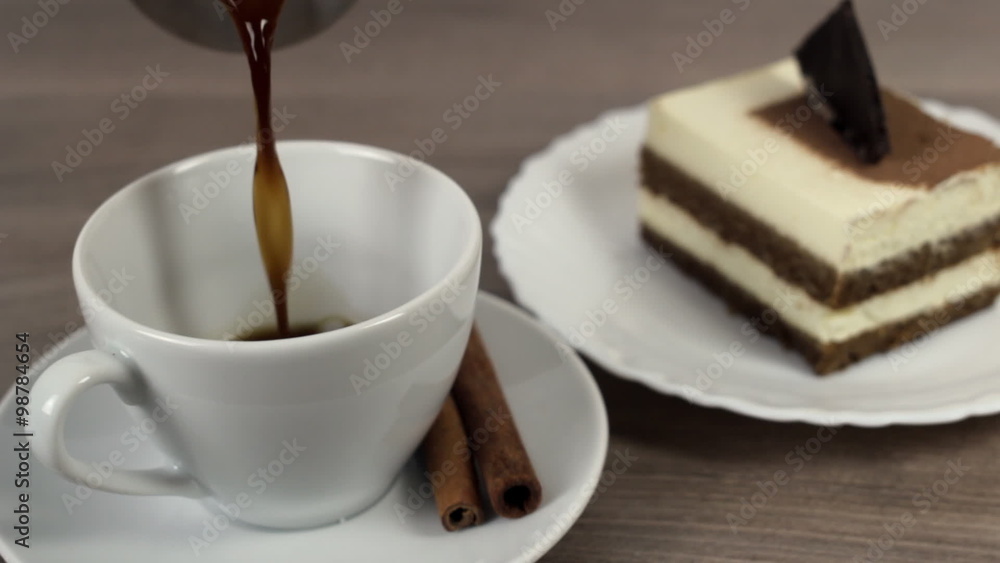 Coffee poured into a white cup on a wooden table with cake and cinnamon Coffee poured into a white cup on a wooden table with cake and cinnamon