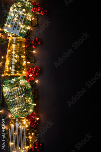 A stack of vintage vases with warm string lights on dark background. Cozy interior details. Top view  copy space.