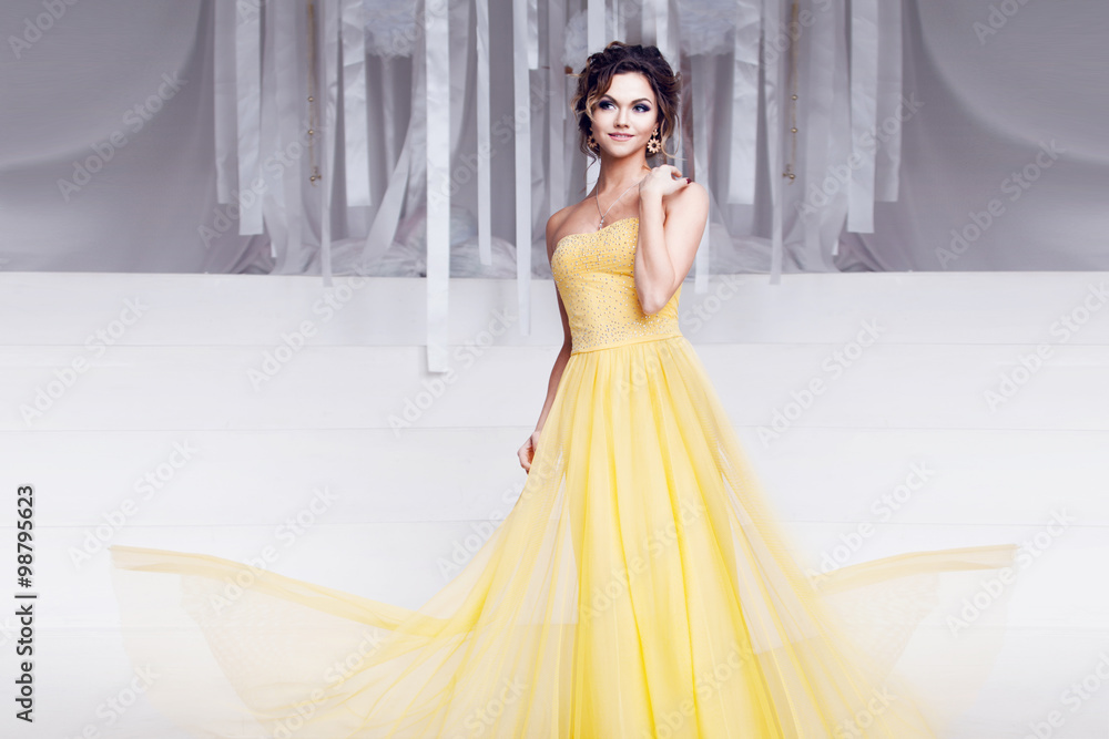 Fototapeta premium smiling woman in yellow evening dress and with beautiful hairstyle, party