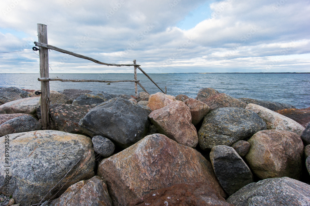 Wooden fence goes into the sea over the rocks