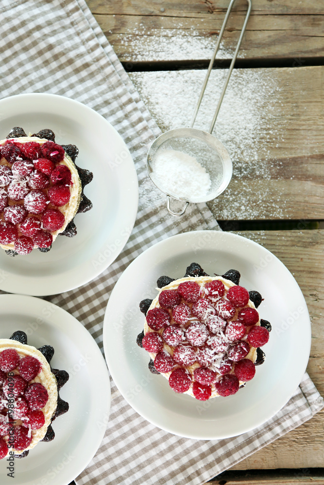 Sweet cakes with raspberries on light wooden background Sweet cakes with raspberries on light wooden background