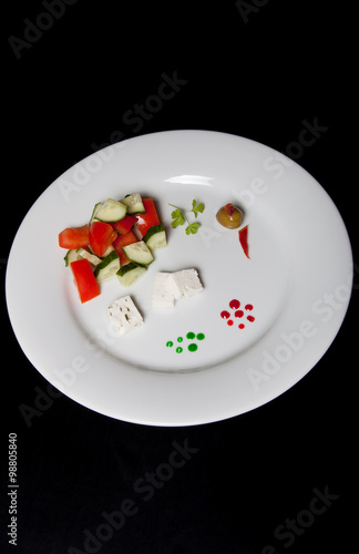 White plate with fresh salad on a black table or background