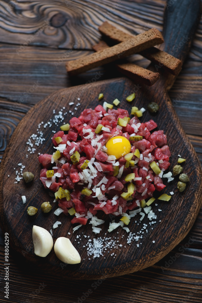 Wooden rustic cutting board with beef tartar, high angle view Wooden rustic cutting board with beef tartar, high angle view