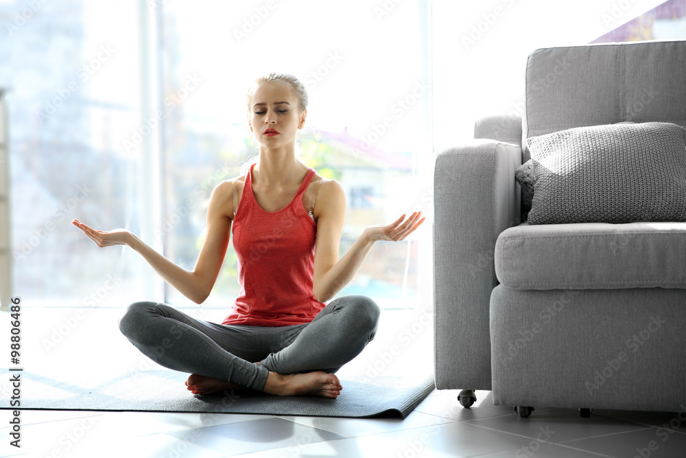 Young woman meditating in the room Young woman meditating in the room