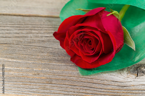 Happy Valentines day with single freshly cut red rose on wood