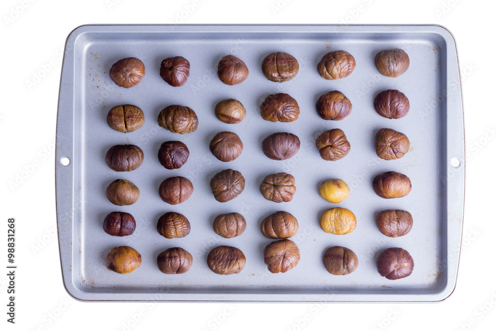 Whole roasted chestnuts on a roasting tray Whole roasted chestnuts on a roasting tray