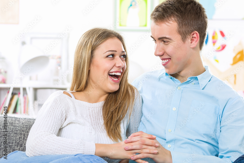 Young couple sitting on the couch and laughing joyfully Young couple sitting on the couch and laughing joyfully