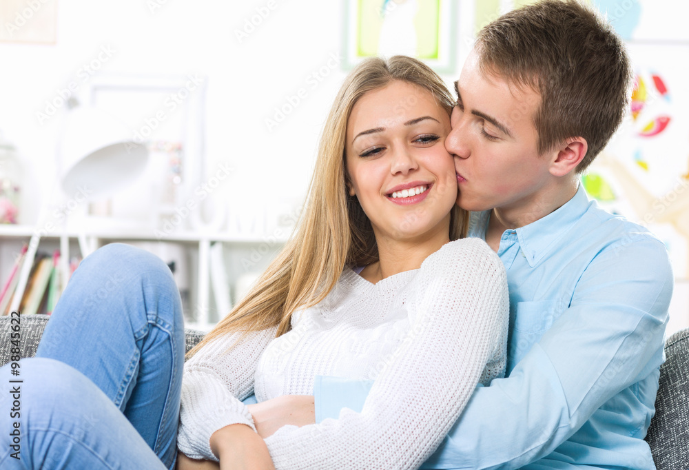 Young lovers hugging on the couch and kissing Young lovers hugging on the couch and kissing