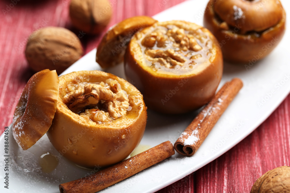 Baked apples on plate on red wooden table Baked apples on plate on red wooden table