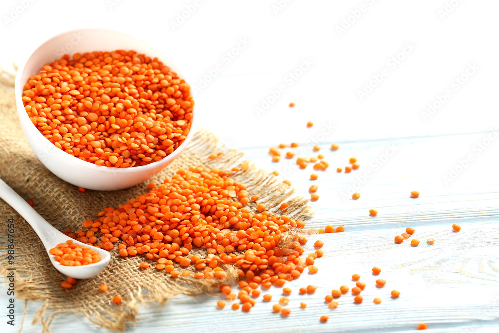 Red lentils in bowl on a blue wooden table Red lentils in bowl on a blue wooden table
