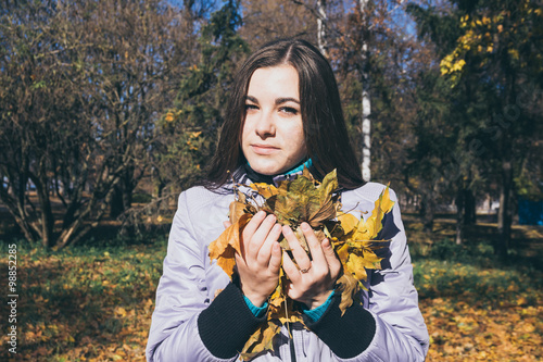 Девочка-подросток и охапка желтых осенних листьев