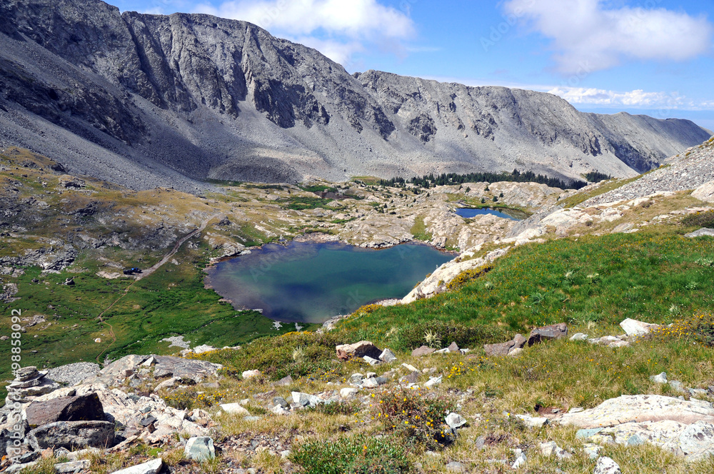 High altitude clear alpine lakes in the Rocky Mountains, as viewed from a mountain summit above while hiking and backpacking.