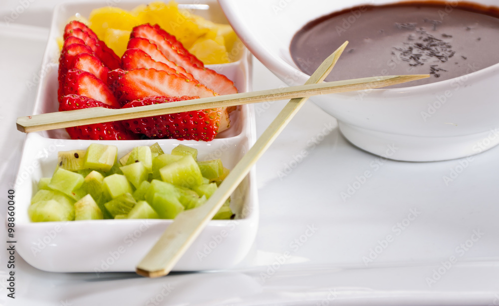 Cut fruit and molten chocolate ready to prepare a few delicious sweet skewers Cut fruit and molten chocolate ready to prepare a few delicious sweet skewers