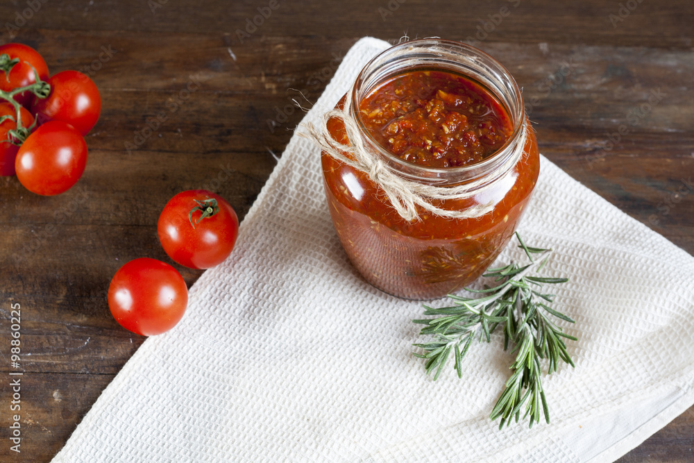 Tomato sauce (jam) in glass jar with parsley and fresh tomatos on dark wooden table, selective focus. Tomato sauce (jam) in glass jar with parsley and fresh tomatos on dark wooden table, selective focus.