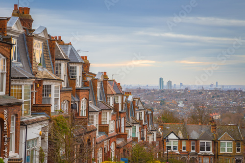 Canvas Print Traditional British brick houses on a cloudy morning with east London at background