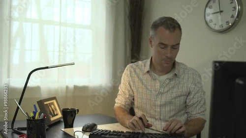 A man works at a clean desk with a computer