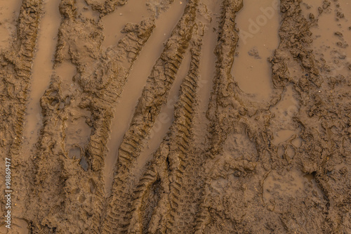 Texture of wet brown mud with bicycle tyre tracks
