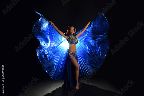 Belly dancer woman in blue costume with wings on dark background photo